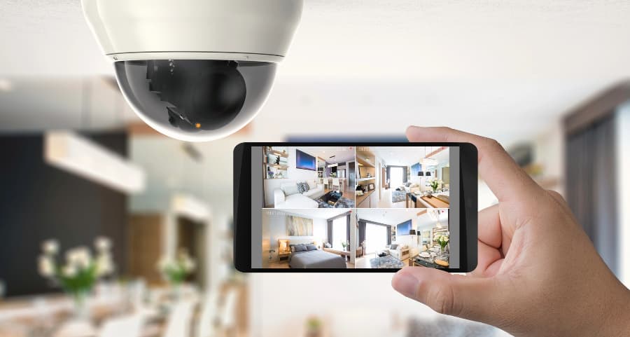 Homeowner holding smartphone with video feed from security cameras in Albuquerque